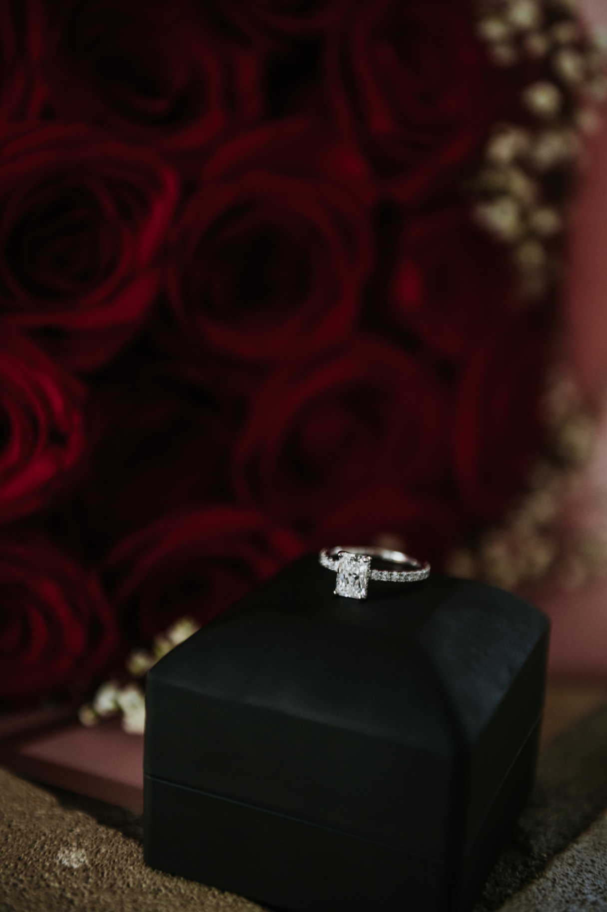 Riziane's engagement ring beside burgundy roses